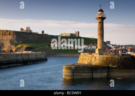 Der Leuchtturm auf Whitby Pier mit St. Hilda Abtei und Str. Marys Kirche auf den Klippen im Hintergrund Stockfoto