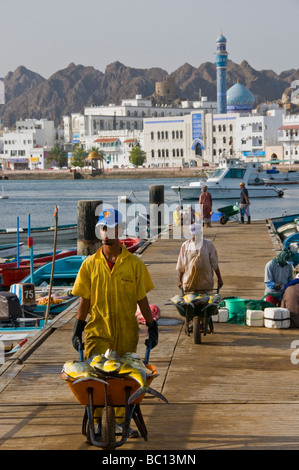 Fischer auf dem Fischmarkt von Mutrah mit alten Muscat im Hintergrund Stockfoto