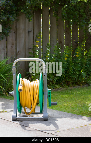 Gartenschlauch Rohr auf Walze in ländlichen Bauerngarten, Wasserblumen Stockfoto