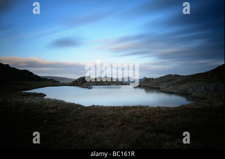 Eine Langzeitbelichtung ein Lakeland Tarn auf der Seathwaite Fjälls oben Borrowdale im englischen Lake District, Cumbria, England Stockfoto