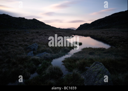 Eine Langzeitbelichtung ein Lakeland Tarn auf der Seathwaite Fjälls oben Borrowdale im englischen Lake District, Cumbria, England Stockfoto