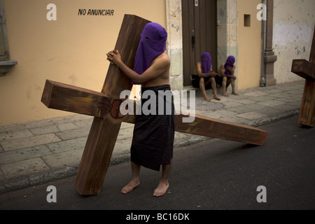 Ein Büßer trägt ein Kreuz bei einer Prozession der Karwoche in Oaxaca, Mexiko. Stockfoto