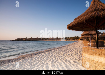 Strohgedeckten Sonnenschirmen und Windschutz an einem einsamen Strand Stockfoto
