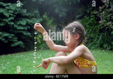 Kleines Mädchen zählen die Blumen in ihrem Daisy-chain Stockfoto
