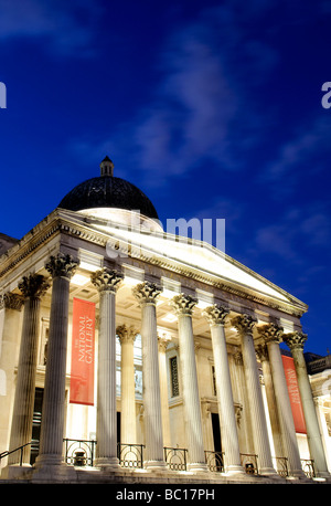 LONDON, Großbritannien - die National Gallery am Trafalgar Square bei Nacht. Der Platz wurde erbaut, um Admiral Horatio Nelsons Sieg in der Schlacht von Trafalgar zu würdigen. Er dient sowohl als historische Stätte als auch als zentraler Knotenpunkt für kulturelle und gesellschaftliche Veranstaltungen. Stockfoto