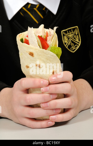 Schulmädchen halten einen Chicken Salat wickeln Sie in gepflegte Hände Stockfoto