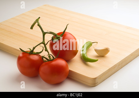 Eine Reihe von Tomaten, Knoblauch und Chili auf ein Schneidbrett aus Holz gelegt. Stockfoto