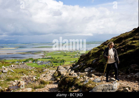 Eine Frau mit einem Gehstock Klettern Croagh Patrick in County Mayo, Irland Stockfoto