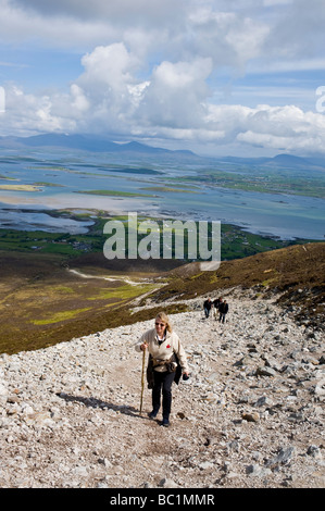 Eine Frau mit einem Gehstock Klettern Croagh Patrick in County Mayo, Irland Stockfoto