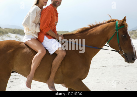 Mid-Adult paar Reiten am Strand Stockfoto