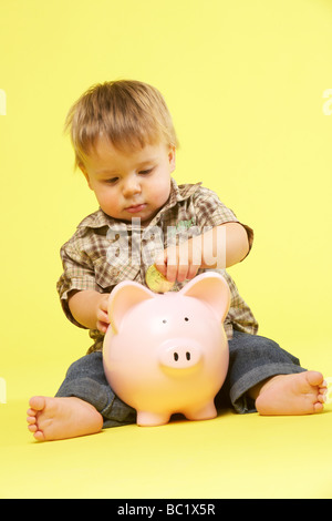 Kleinkind im Studio mit Sparschwein Stockfoto