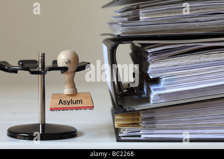 Stempel mit Inschrift Asyl neben einem Haufen von Dateien Stockfoto