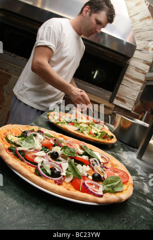 Pizza belegt mit lecker aussehende Gemüse von Koch in einem Restaurant gemacht Stockfoto