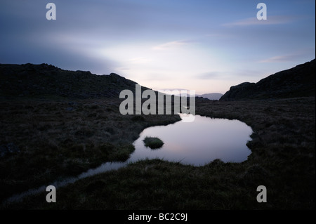 Eine Langzeitbelichtung ein Lakeland Tarn auf der Seathwaite Fjälls oben Borrowdale im englischen Lake District, Cumbria, England Stockfoto