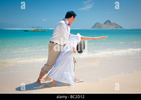 Asiatische Braut und Bräutigam tanzen und Tauchen Sie während sie einen am Strand von Lanikai, Kailua, Hawaii Spaziergang Stockfoto