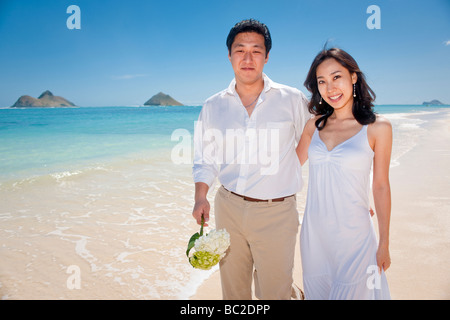 Asiatische Braut und Bräutigam spazieren Sie am Strand von Lanikai, wie sie ihr Leben als Ehepaar nach ihrer Hochzeit freuen Stockfoto