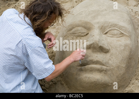 Ein Künstler arbeitet auf eine Sandskulptur an einem Strand am Südufer des Flusses Themse London UK Stockfoto