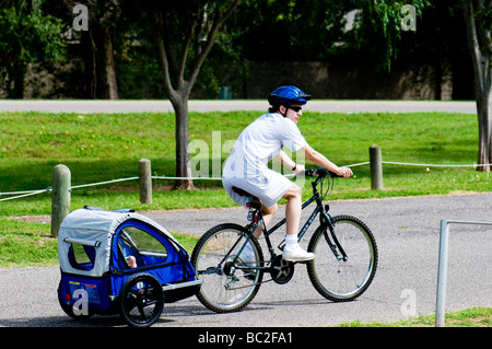 Eine junge Mutter schleppt ihr Kind in ein Fahrrad Anhänger in den USA. Stockfoto