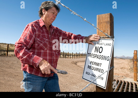 Eine Frau legt ein No Trespassing Schild an der uns mexikanischen Grenze in Arizona. Stockfoto