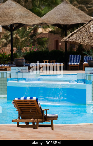 Eine hölzerne Sonnenliege neben einem Schwimmbad in einer Luxus-Ferienanlage Stockfoto