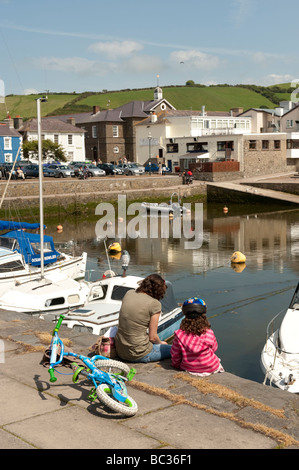 Mutter und Tochter sitzen in der Sonne am Aberaeron Inner harbour Ceredigion Wales UK Sommernachmittag Stockfoto