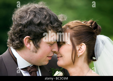 Ein frisch verheiratetes Paar nah an einander und Nasen in einer liebevollen Umarmung berühren Stockfoto