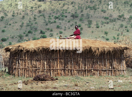 Massai Frau ruht auf ihrer Hütte nach abdecken mit frischem Kuhdung Masai Mara National Reserve Kenia Afrika Stockfoto