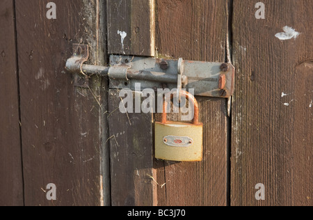 Nahaufnahme von rostigen Vorhängeschloss sichern Schiebetür Schraube auf Holz verkleidete Garage/Schuppen/Werkstatt Stockfoto