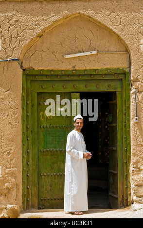 Jungen Mann vor traditionellen Haus aus Lehm und Ziegel in der Stadt Al Hamra Sultanate von Oman Stockfoto