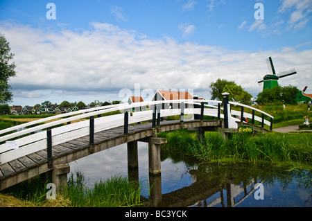 Fußgängerbrücke über einen Kanal an De Zaanse Schans, Niederlande, mit Windmühle im Hintergrund Stockfoto