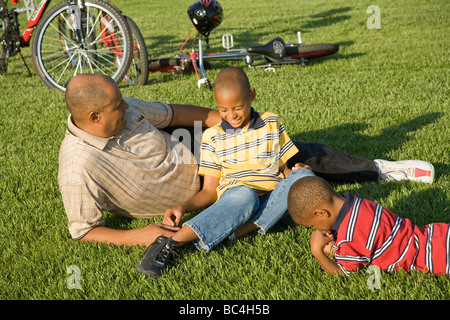 Vati jungen Jugendlichen Menschen Vaters Kinder sprechen das Gespräch mit jedem anderen entspannenden Gras Fahrrad Gespräch 5-9 Jahre Jahr alt Stockfoto