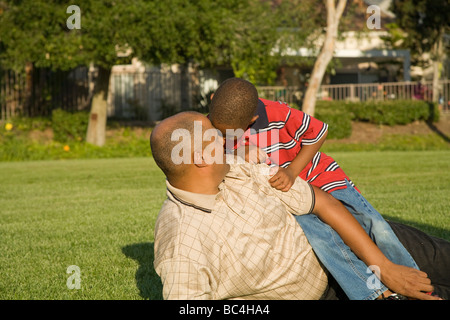 Gespräch, sprechen. Afro-Amerikaner Vater und Sohn Hänseleien und zusammen draußen auf dem Rasen spielen. Herr © Myrleen Pearson Stockfoto