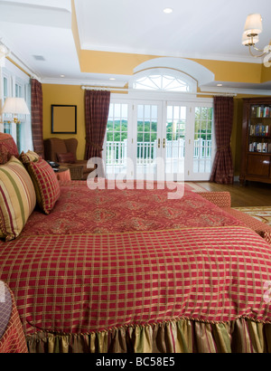 schöne Schlafzimmer mit King size Bett Büchergestell und Französisch Türen zur Terrasse mit wunderschönem Ausblick Stockfoto