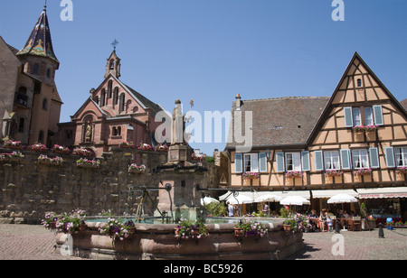 Eguisheim Elsass Frankreich EU Menschen auf einem Platz in dieser mittelalterlichen Innenstadt im Schatten des Schlosses 8thc auswärts Stockfoto