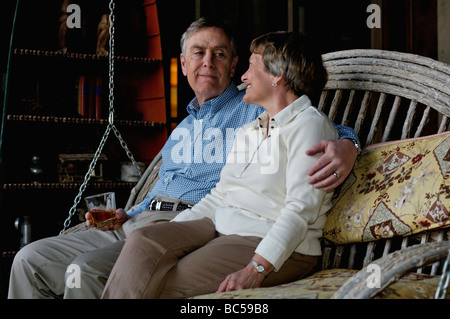 Älterer Mann und Frau sitzen auf einer Portal-Schwingen und genießen jede andere Firma Stockfoto