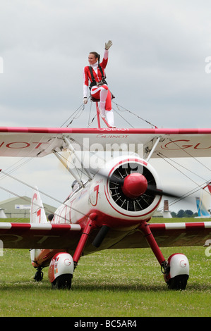 Team Guinot Barnstorming Doppeldecker rollt heraus mit jungen Frau geschnallt Flügel winkt in die Menge Stockfoto