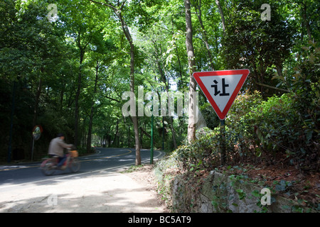 Ein Mann auf einem Fahrrad fährt, vorbei an einem Straßenschild in der Nähe von Hangzhou, China Stockfoto