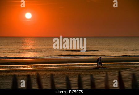 Ein paar zu Fuß am Strand bei Sonnenuntergang in der Nähe von Zandvoort in den Niederlanden Stockfoto