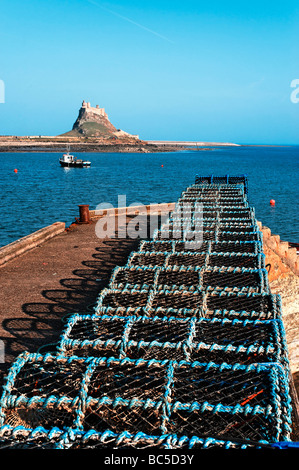 Lindisfare Hafen, Hummerfallen aufgereiht auf dem Steg. Lindisfarne Schloß in der Ferne Stockfoto