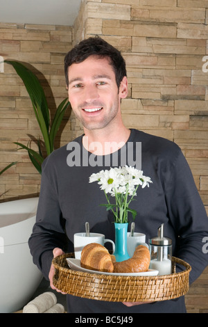 Junger Mann tragenden Tablett mit Frühstück, Lächeln, Porträt Stockfoto