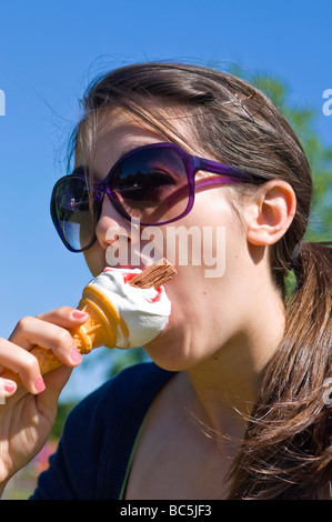 Vertikale Porträt eines attraktiven Teenager Mädchen mit großen Sonnenbrillen ein 99 Eis essen, an einem sonnigen Tag Stockfoto