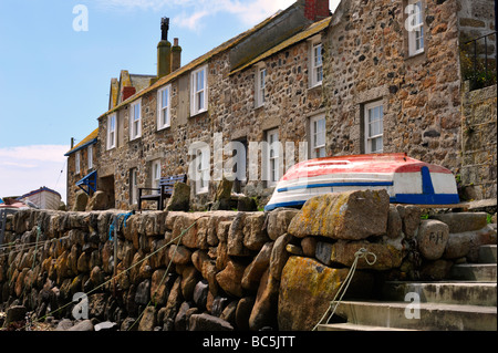 MOUSEHOLE, CORNWALL, Großbritannien - 09. JUNI 2009: Boot vor Fischerhäuschen im Dorf Stockfoto