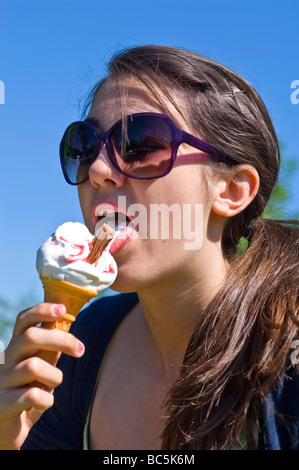 Vertikale Porträt eines attraktiven Teenager Mädchen mit großen Sonnenbrillen ein 99 Eis essen, an einem sonnigen Tag Stockfoto
