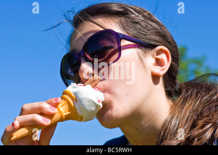 Horizontale Porträt eines attraktiven Teenager Mädchen mit großen Sonnenbrillen ein 99 Eis essen, an einem sonnigen Tag Stockfoto