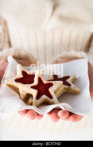 Hände halten Marmelade Kekse auf Serviette- Stockfoto