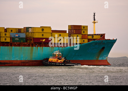 Schlepper drücken eine große Fracht-Container-Schiff in einem Hafen. Stockfoto