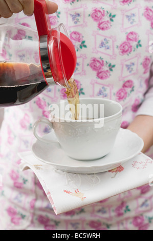 Frau gießt Kaffee in Tasse- Stockfoto