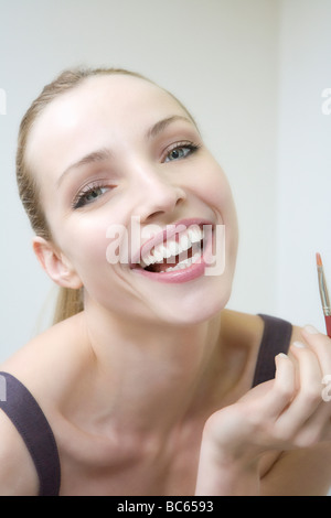 Junge Frau mit Pinsel, lachen, Porträt, Nahaufnahme Stockfoto