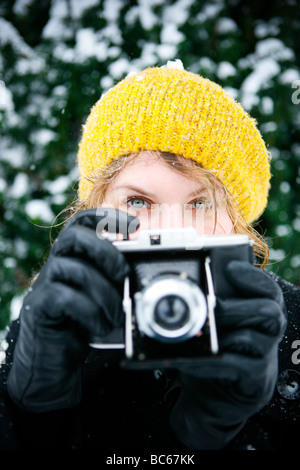 Eine Frau-Fotograf hält eine Großformatkamera in einer Winterlandschaft Stockfoto