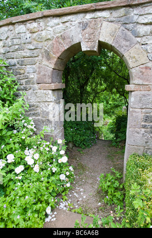 Stein-Torbogen in alten Gartenmauer mit prominenten Keystone hinunter zum geheimen Garten Stockfoto